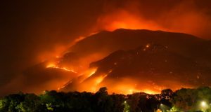 Kemp Weighs Special Session After Georgia Wildfires Smoke rises from a wildfire in southeast Georgia, with burned trees and charred ground visible in the foreground.