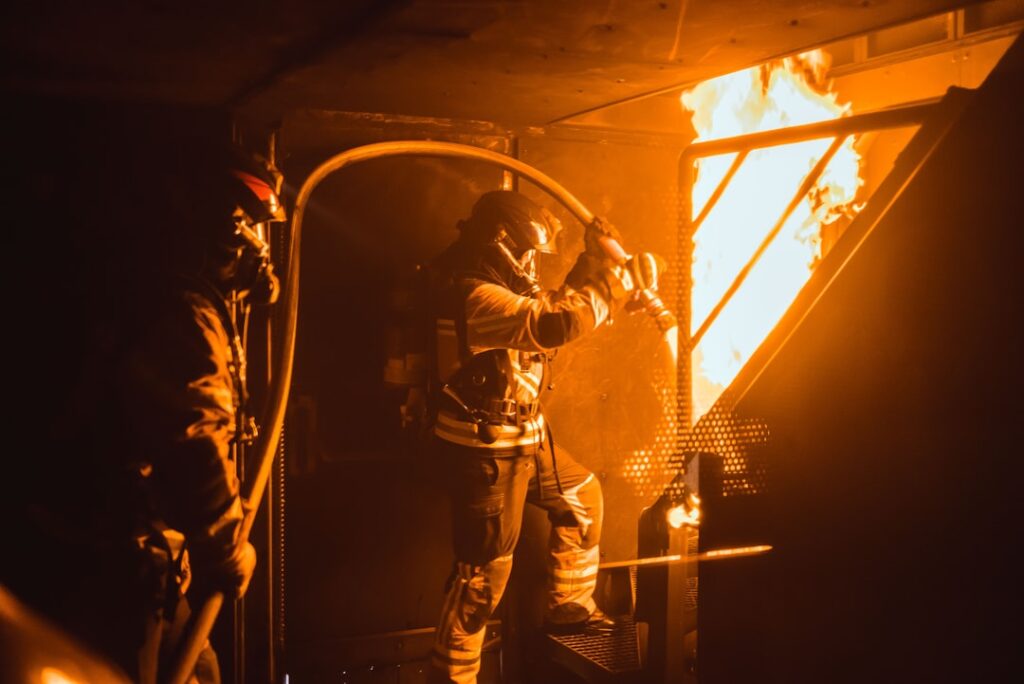 Firefighters battle a blaze in a narrow Manila alley as smoke billows from a residential-commercial building.