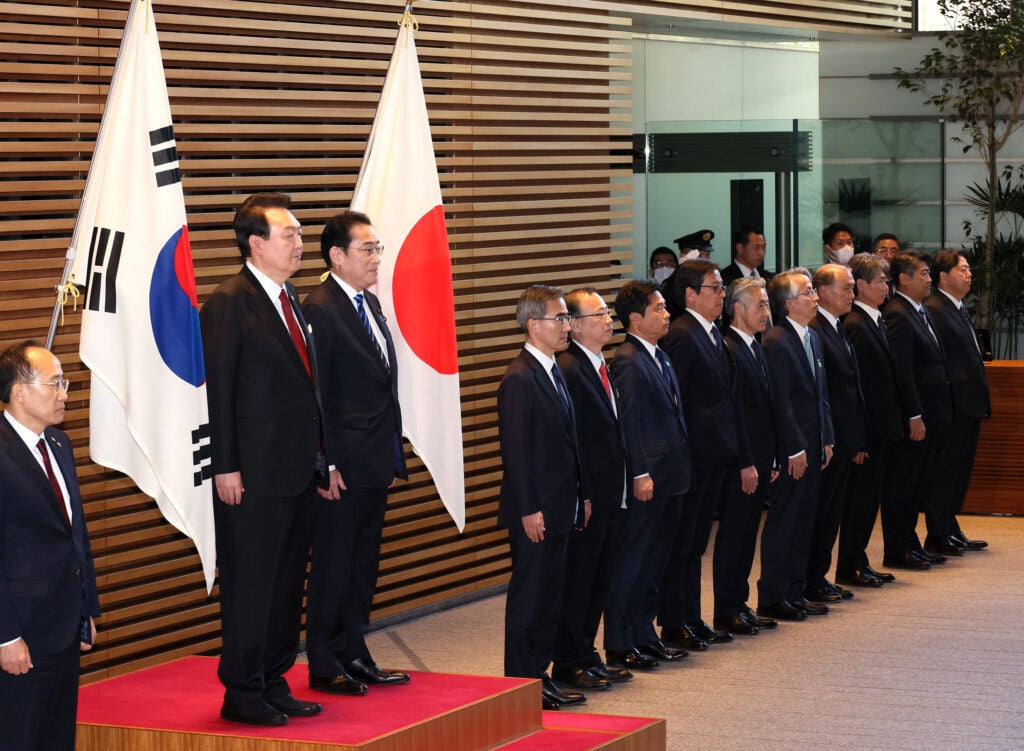 Split-screen video call shows Japanese and Korean officials at desks during marathon trade negotiations.