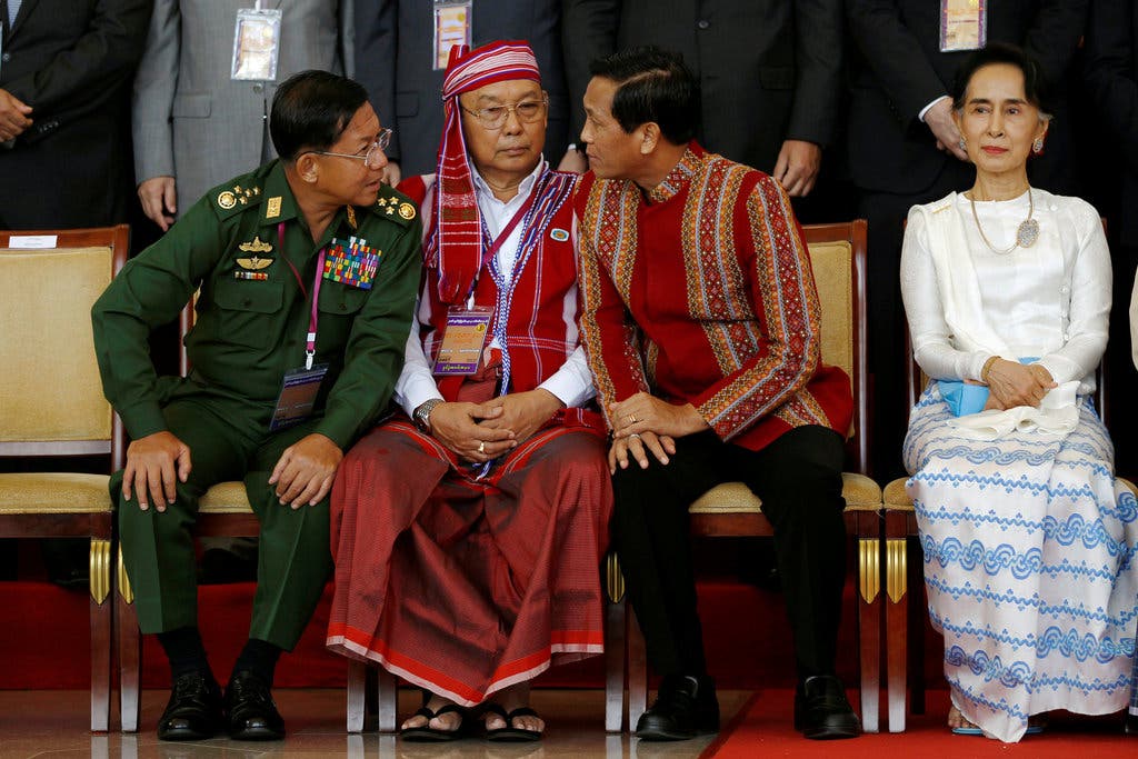Thai officials greet Myanmar military and opposition delegations seated at a long table for peace negotiations.